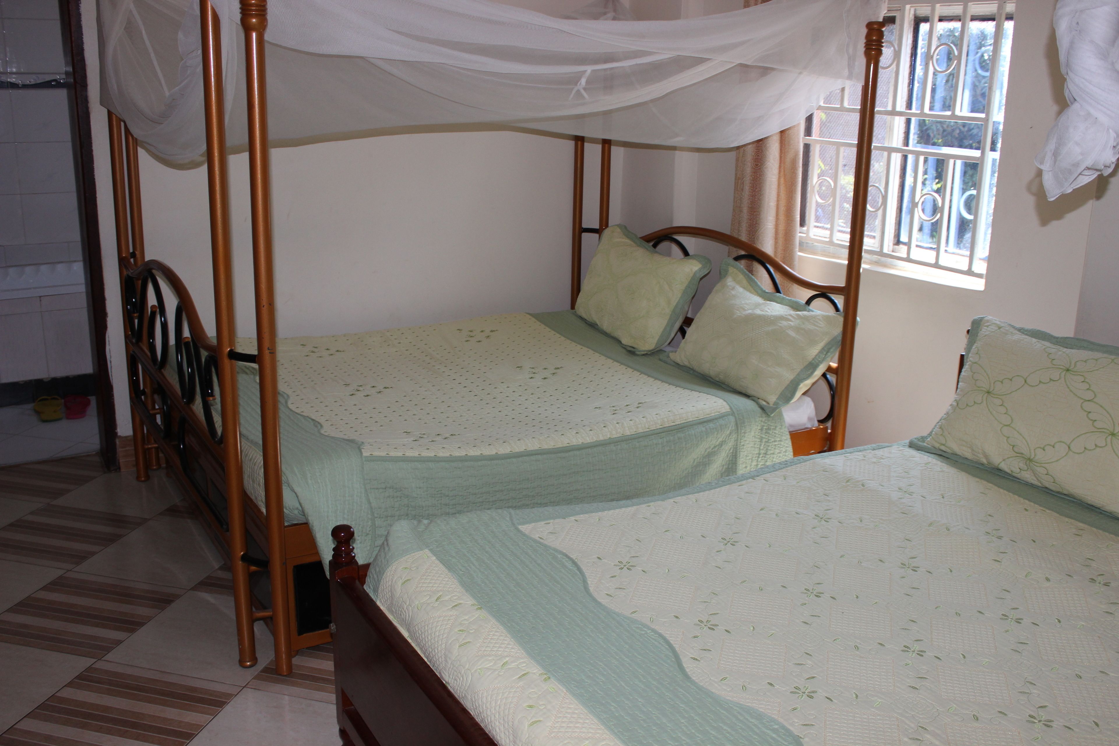 A four-poster bed with a canopy, a wooden headboard, and a window with bars.