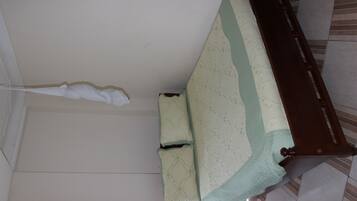 Una cama con estructura de madera, colcha y almohada blanca.
