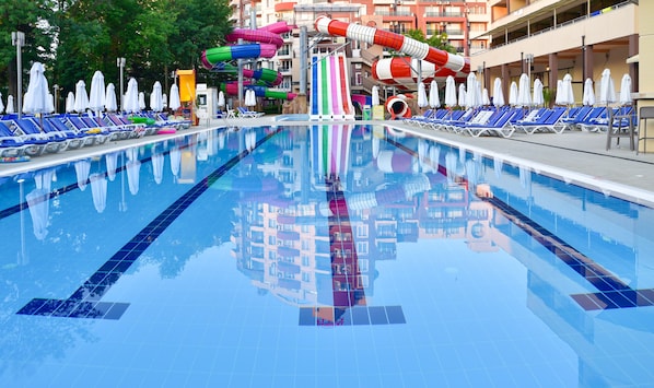 A swimming pool with multiple lanes, a water slide, and lounge chairs. - Hotel Laguna Park & Aqua Club (Sunny Beach)