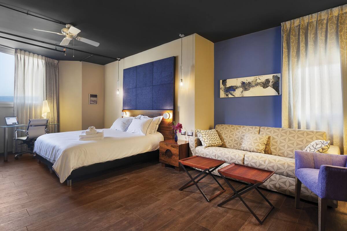 Una habitación de hotel con una cama, un sofá, un escritorio y una silla.