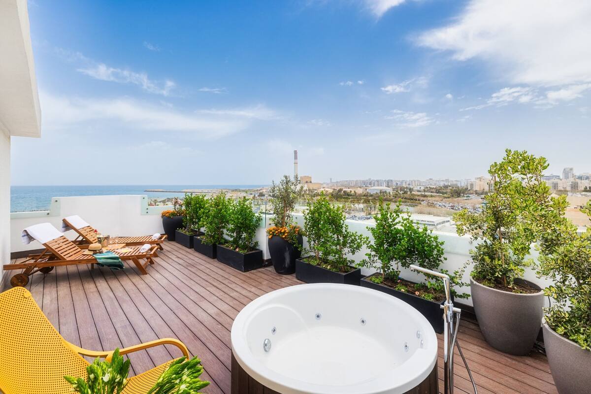 Una terraza en la azotea con un jacuzzi, sillones de descanso y plantas en macetas.