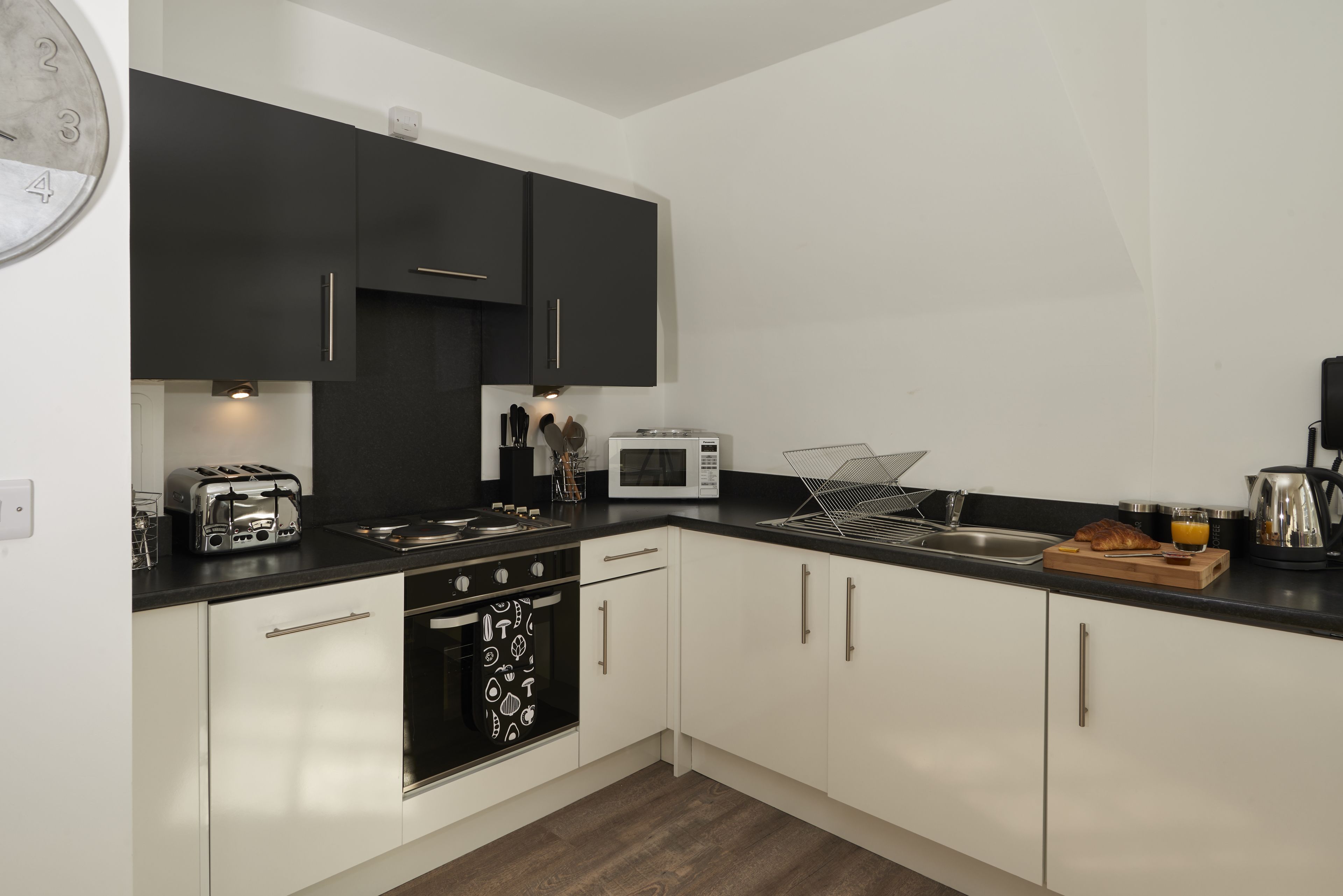 A modern kitchen with black and white cabinets, a microwave, toaster, and a sink.