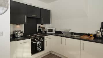 A modern kitchen with black and white cabinets, a microwave, toaster, and a sink.