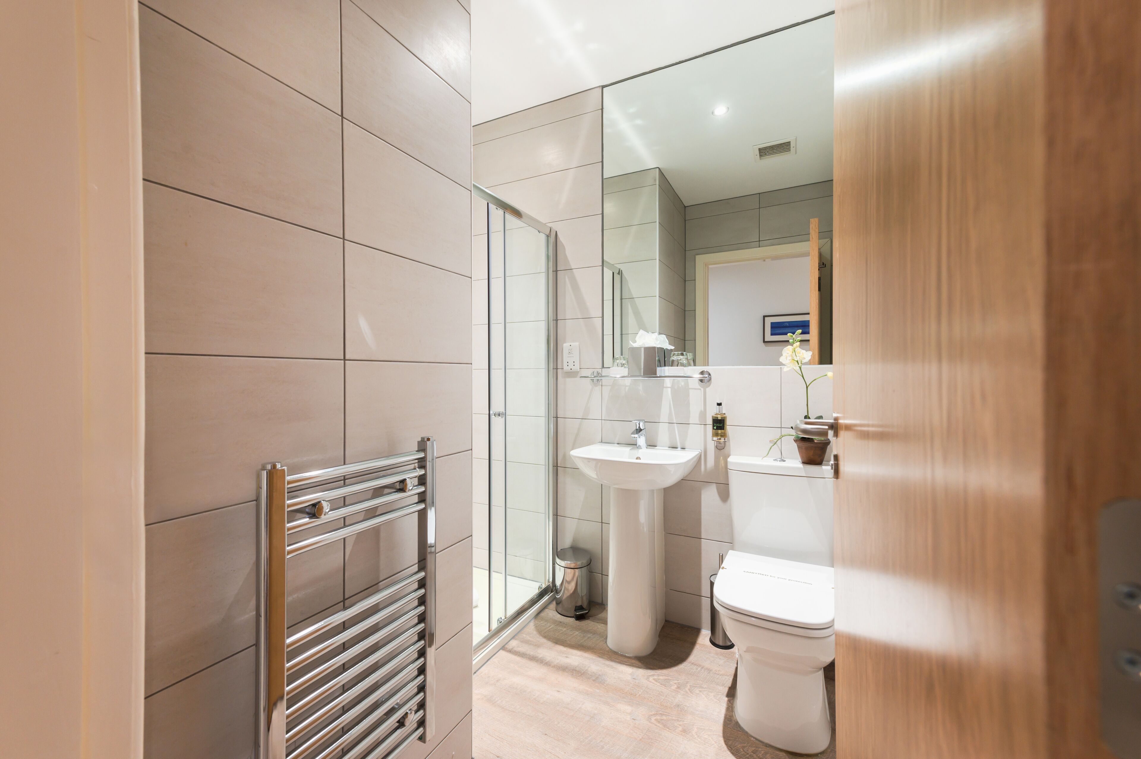 Une salle de bain moderne avec une douche à parois de verre, un lavabo sur colonne et des toilettes.