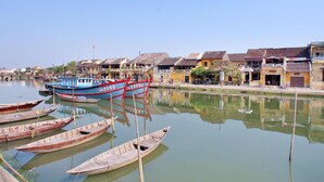 A calm waterway with several boats docked, surrounded by traditional buildings with distinct architectural styles. - Green Boutique Villa (Da Nang)