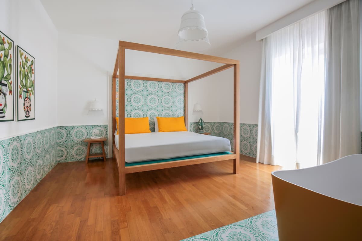 A bedroom with a four-poster bed, a wooden floor, and a patterned wall.