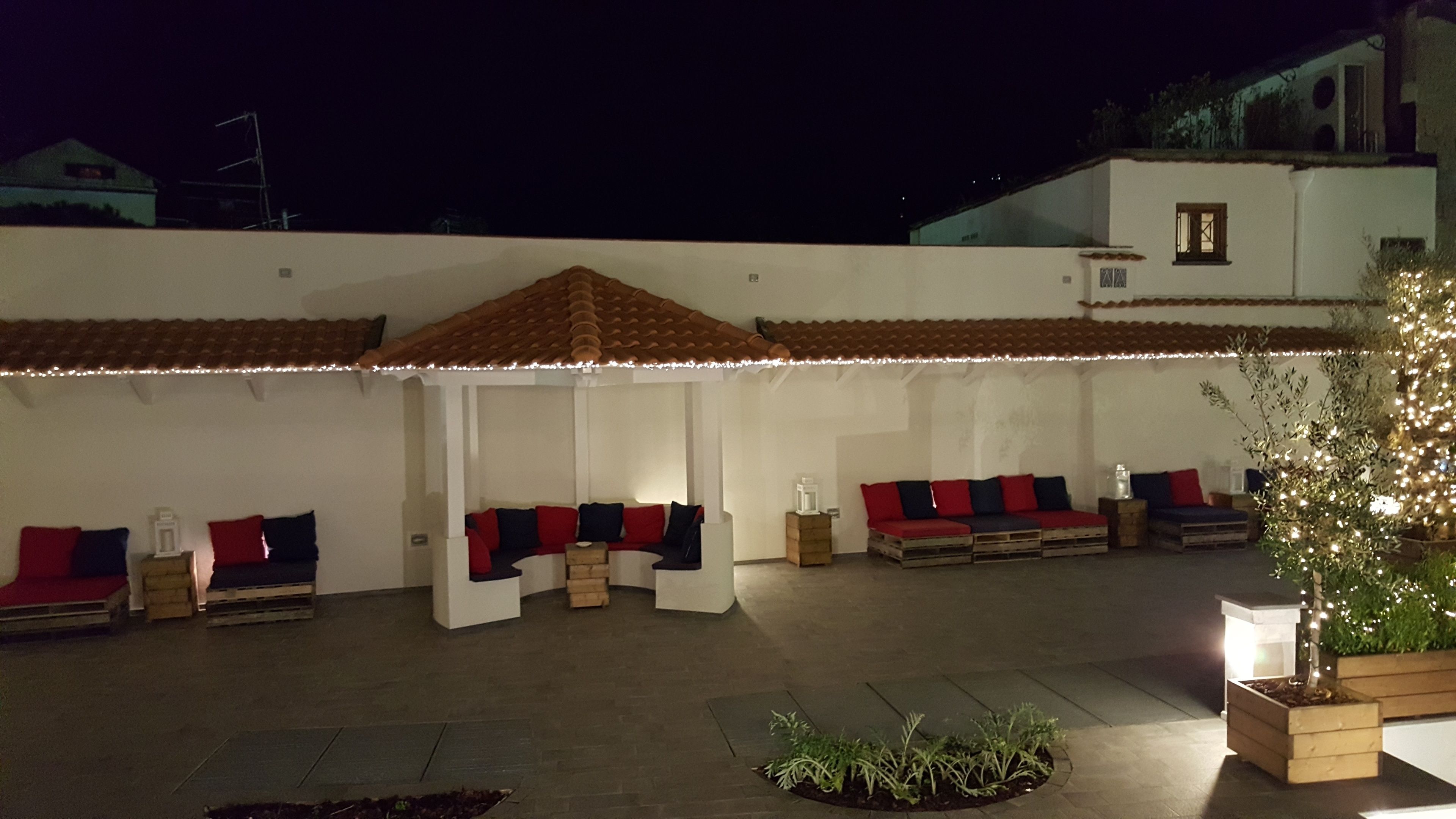 An outdoor seating area with cushioned benches and a tiled roof.