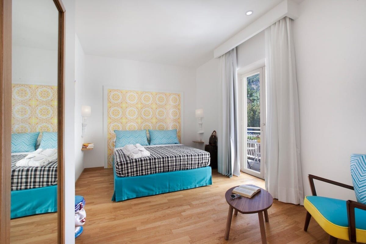 A hotel room with two beds, a small table, and a chair.