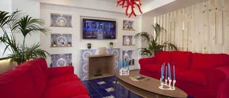 Una sala de estar con sofás rojos, una mesa de centro y un televisor montado en la pared.