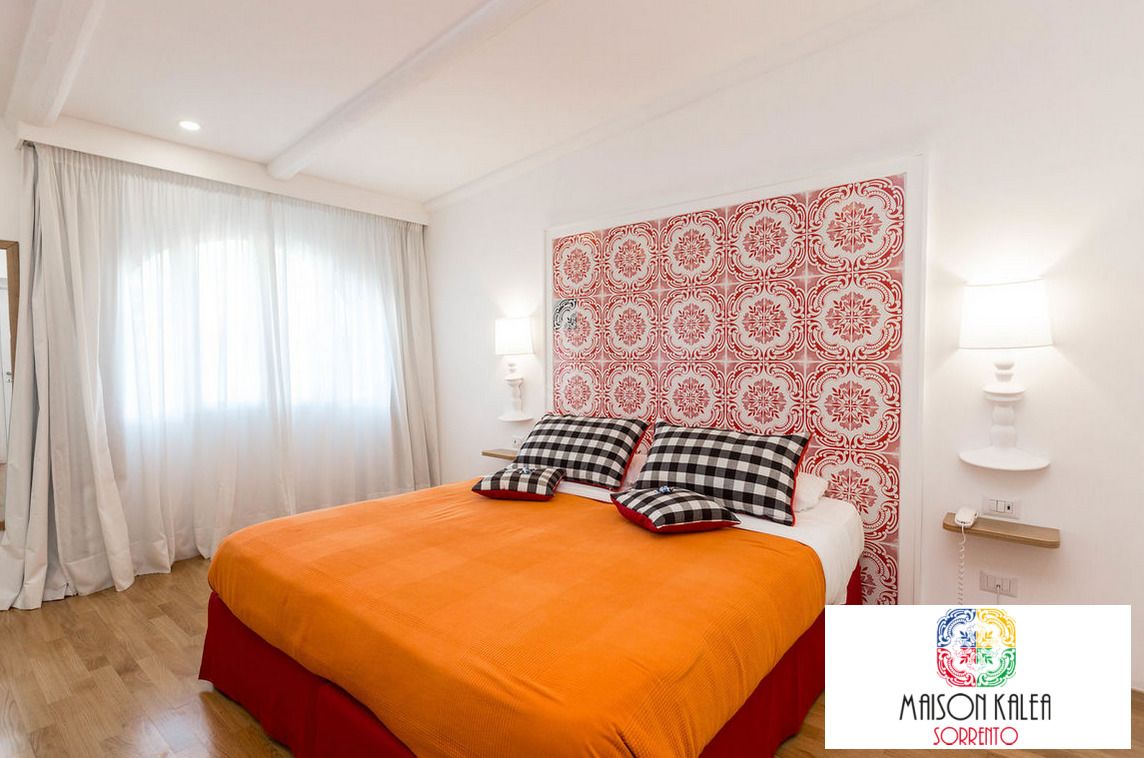 Une chambre d’hôtel avec un grand lit, des murs blancs, une tête de lit à motifs et deux lampes de chevet.