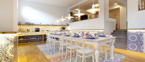 A modern kitchen with a central island, white bar stools, and hanging pendant lights.