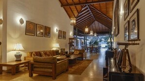 A spacious living room with a high ceiling, wooden beams, a sofa set, a coffee table, and a telescope on a side table. - Villa Republic River View Bentota (Aluthgama)