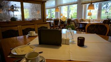 A dining table set with a menu, a cup, a vase with a flower, and a candle.