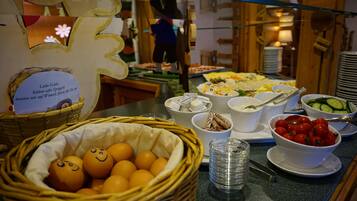 A buffet table with various food items, including a basket of oranges and bowls of food.