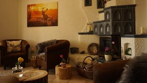 A cozy living room with a fireplace, a painting of a deer, and rustic decor.