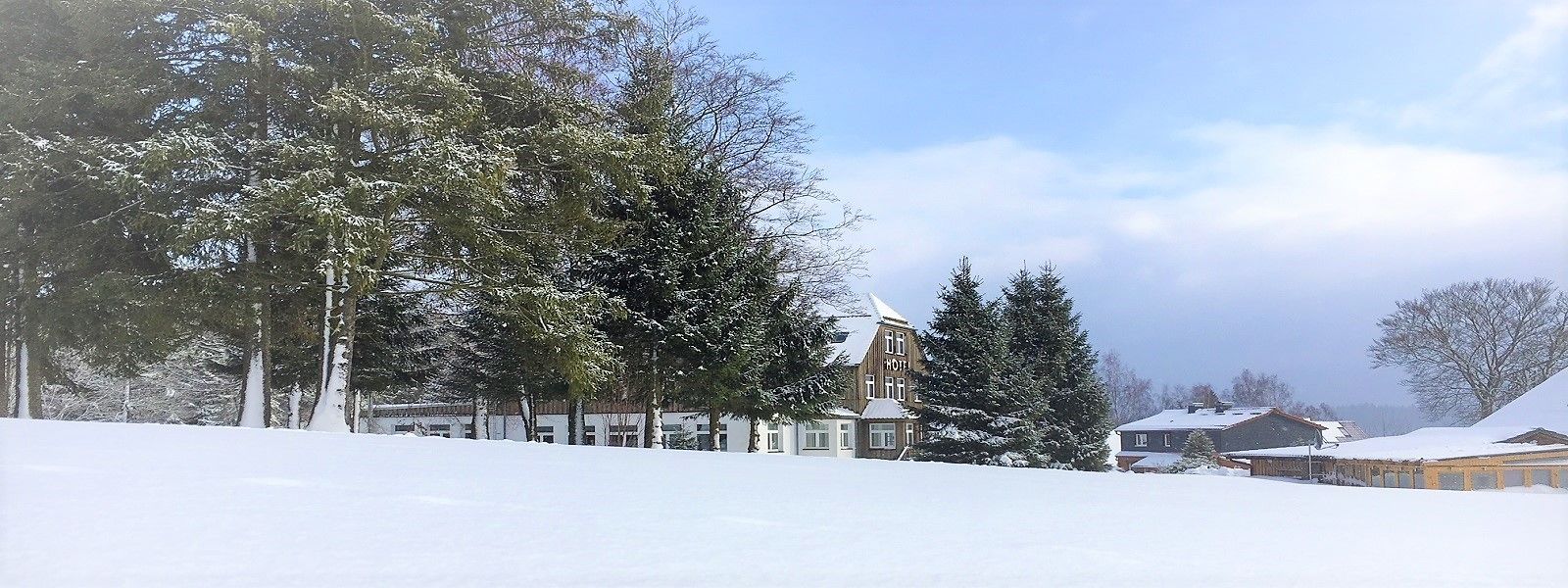A snow-covered landscape with a hotel building and surrounding trees.