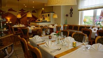 A restaurant with wooden furniture, white tablecloths, and candlelit tables.