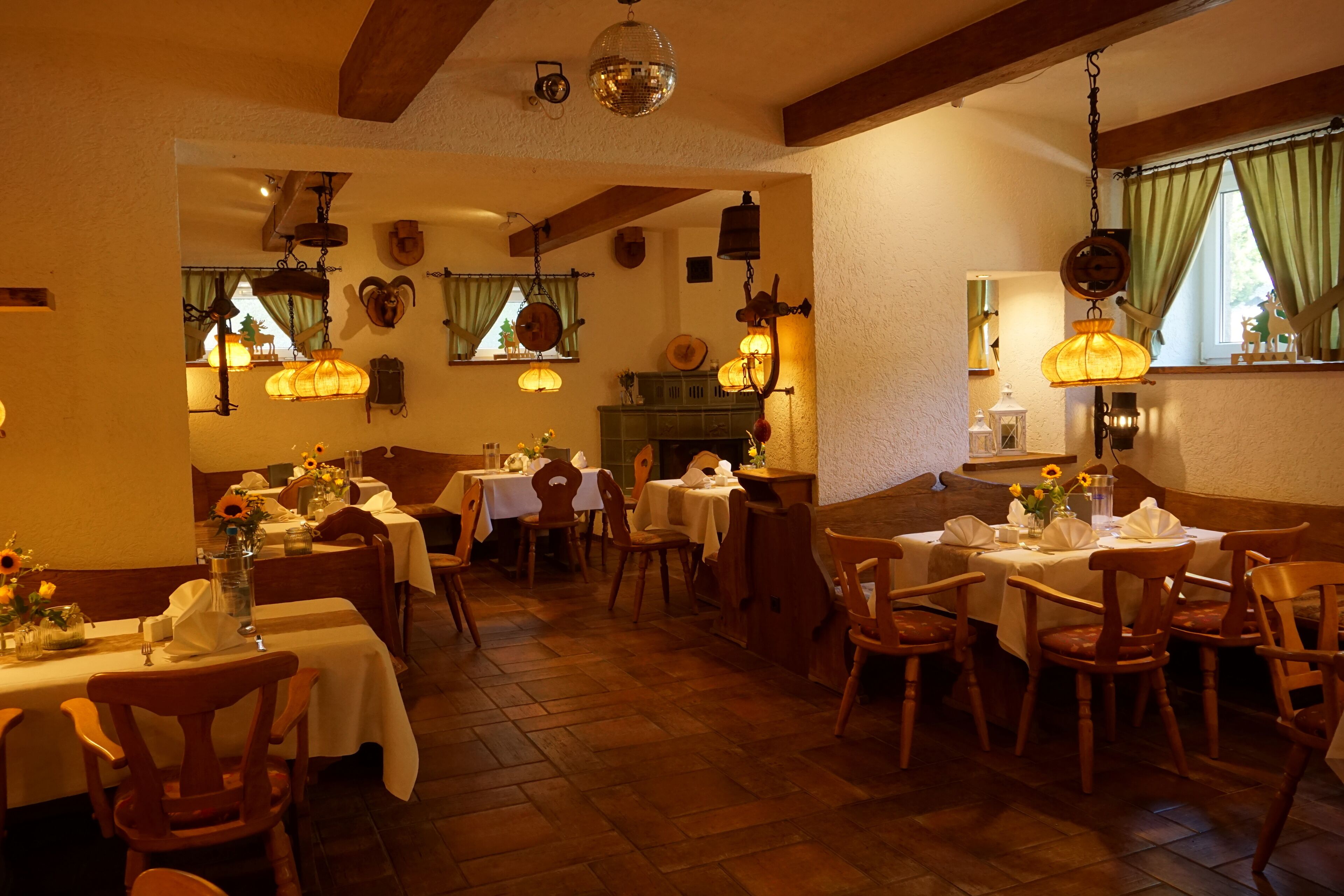 Un comedor con mesas y sillas de madera, lámparas colgantes y una decoración rústica.