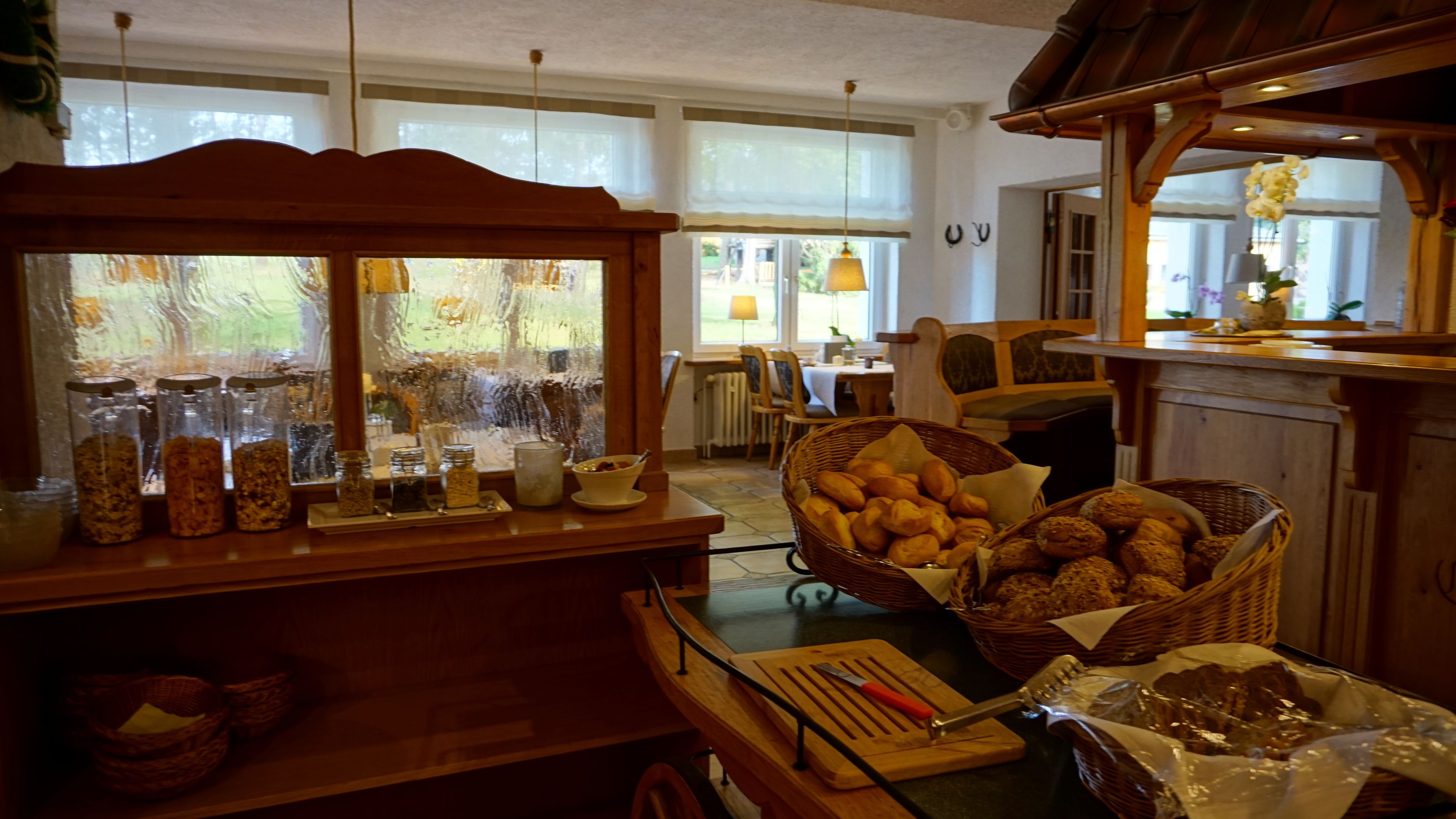 A kitchen with a wooden counter, jars of food, and baskets of bread.