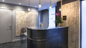 A reception desk with a glass bowl, a chair, and a wall with handwritten notes. - Hôtel Le Mireille (Paris)