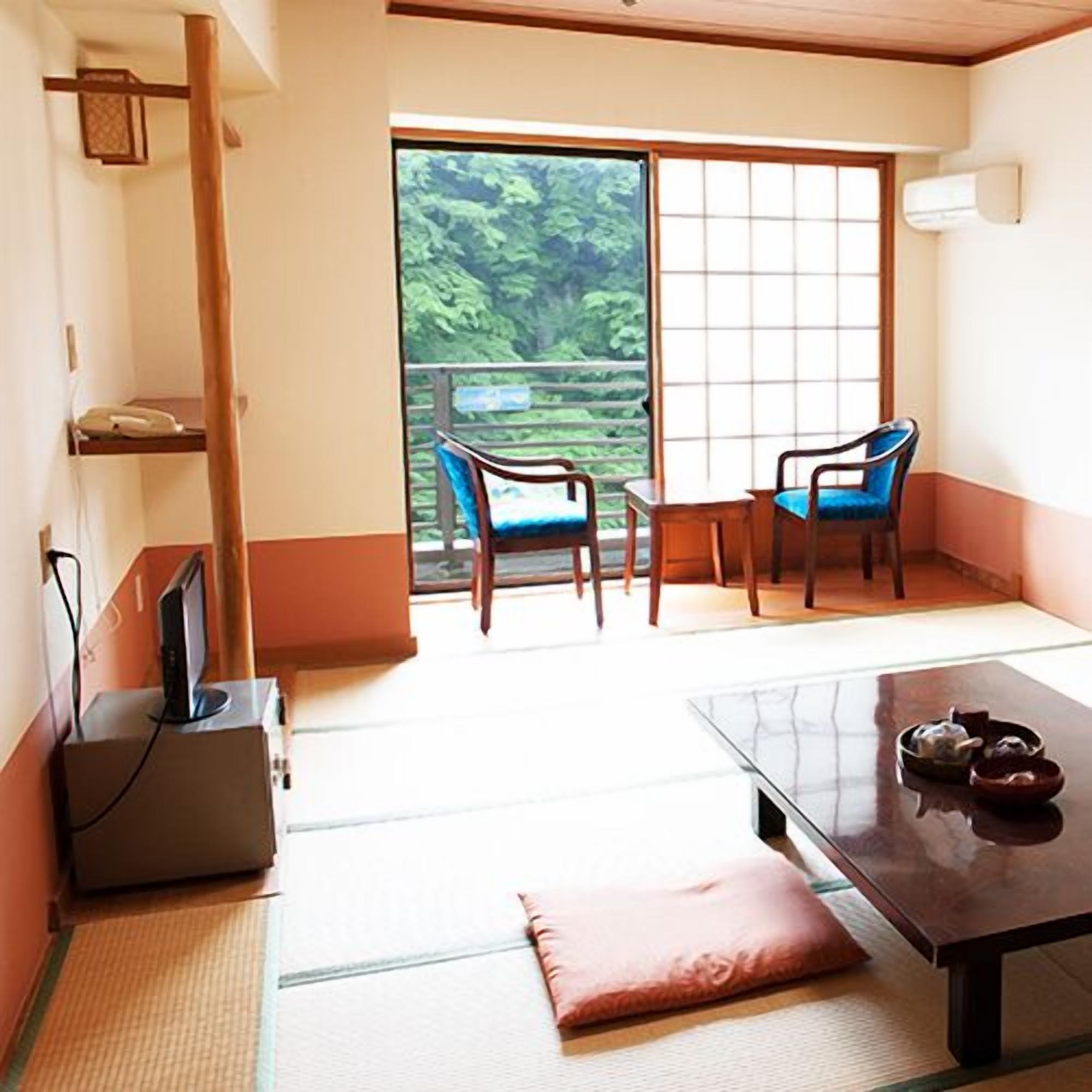 A traditional Japanese room with tatami flooring, a sliding door, and a view of greenery.