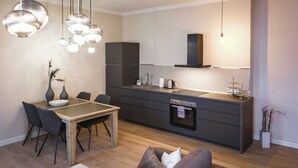 A modern kitchen with a dining table, chairs, and pendant lights. - Bearsleys Downtown Apartments (Riga)