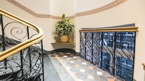 A staircase with a patterned floor, a potted plant, and a decorative railing. - Bearsleys Downtown Apartments (Riga)