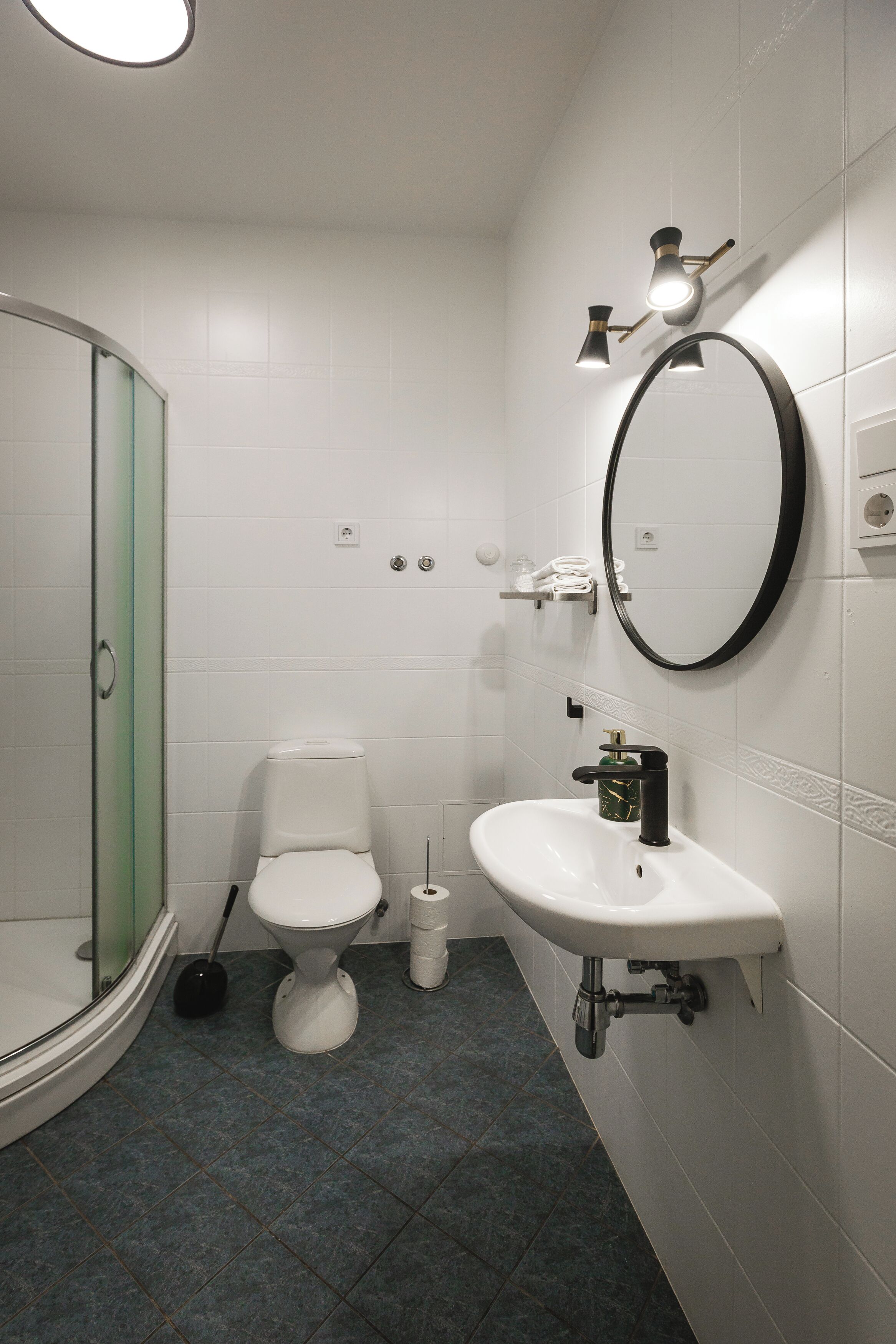 A modern bathroom with a toilet, sink, and glass shower enclosure.