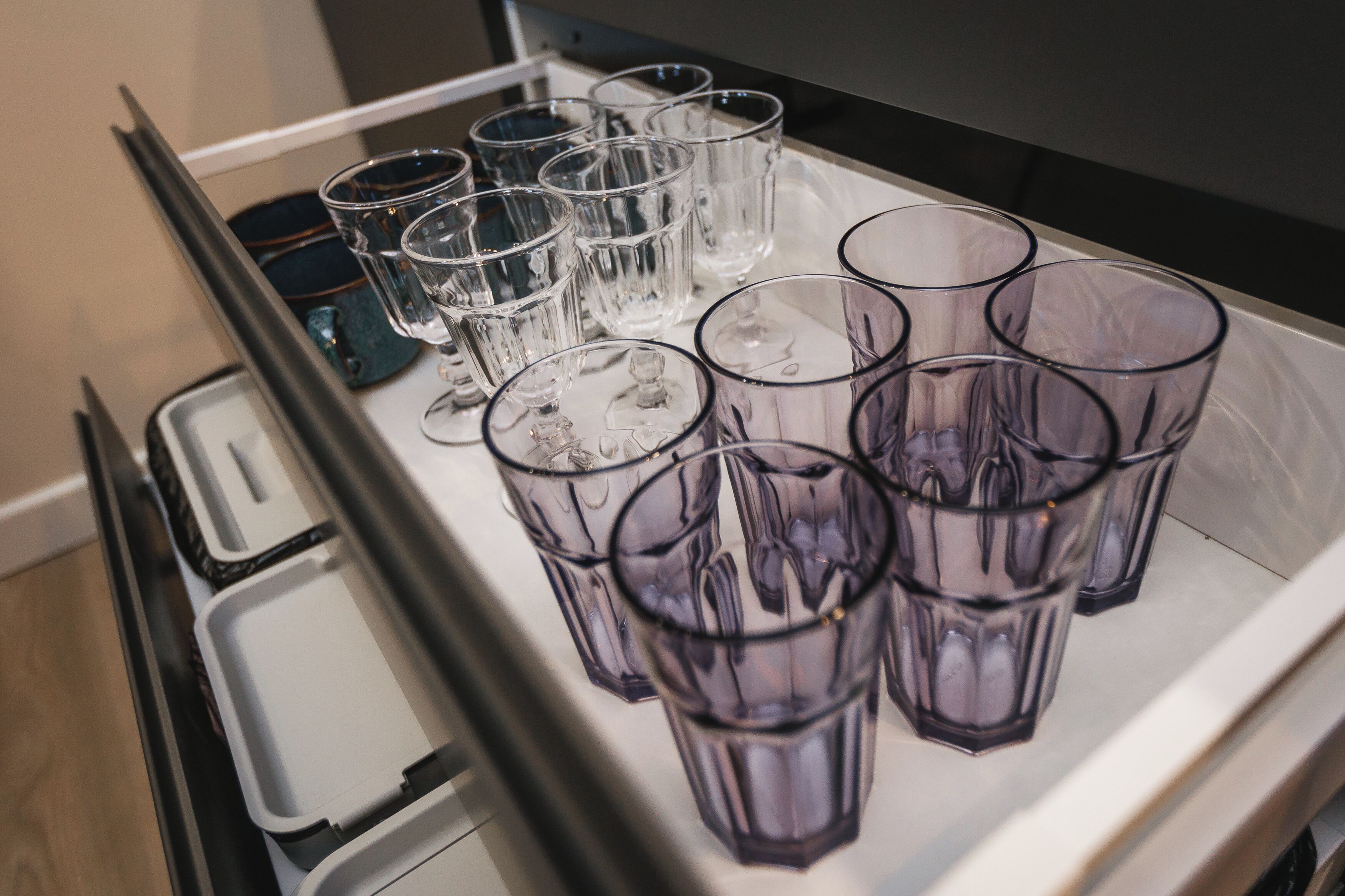 A tray with multiple glasses, some filled with ice, in a kitchen setting.