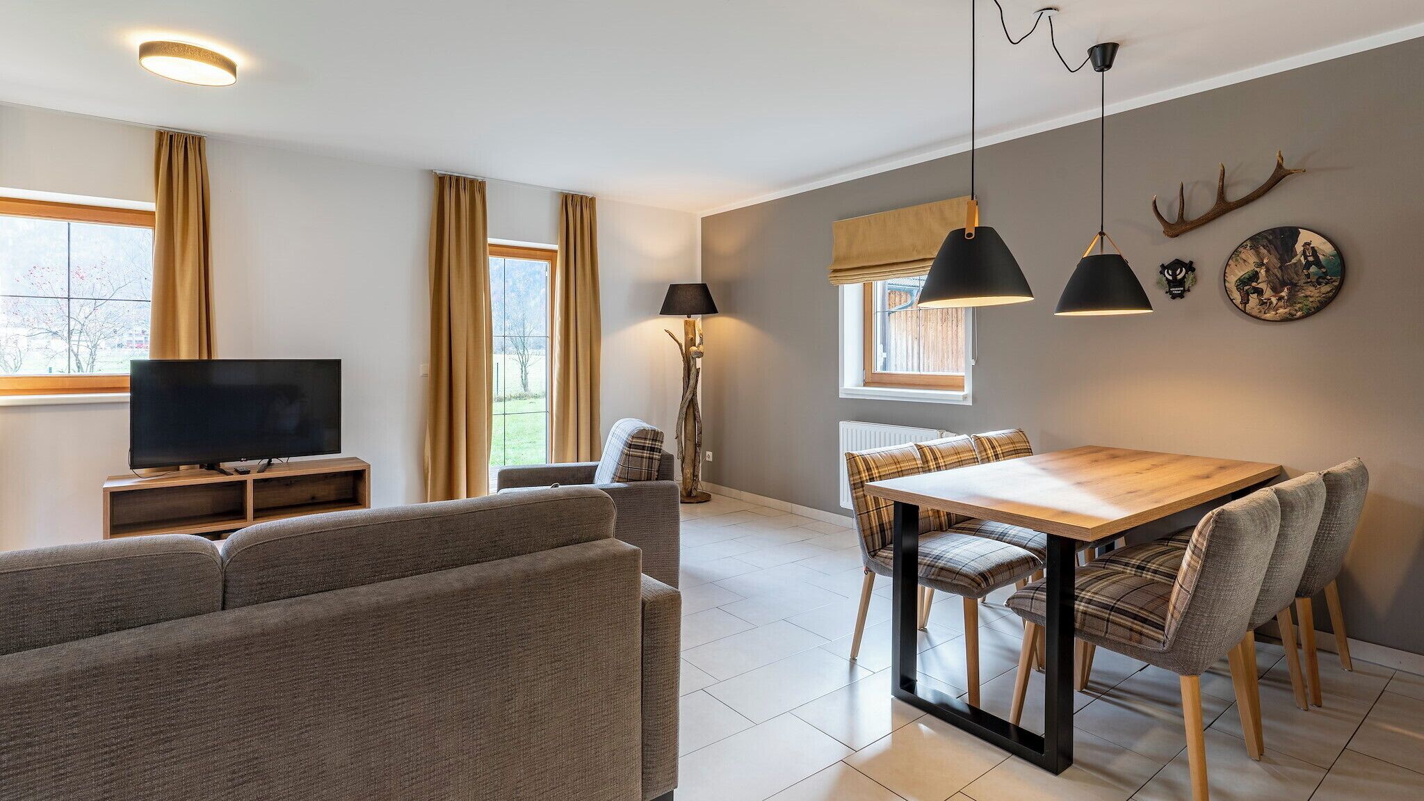 A modern living room with a flat-screen TV, sofa, dining table, and chairs.