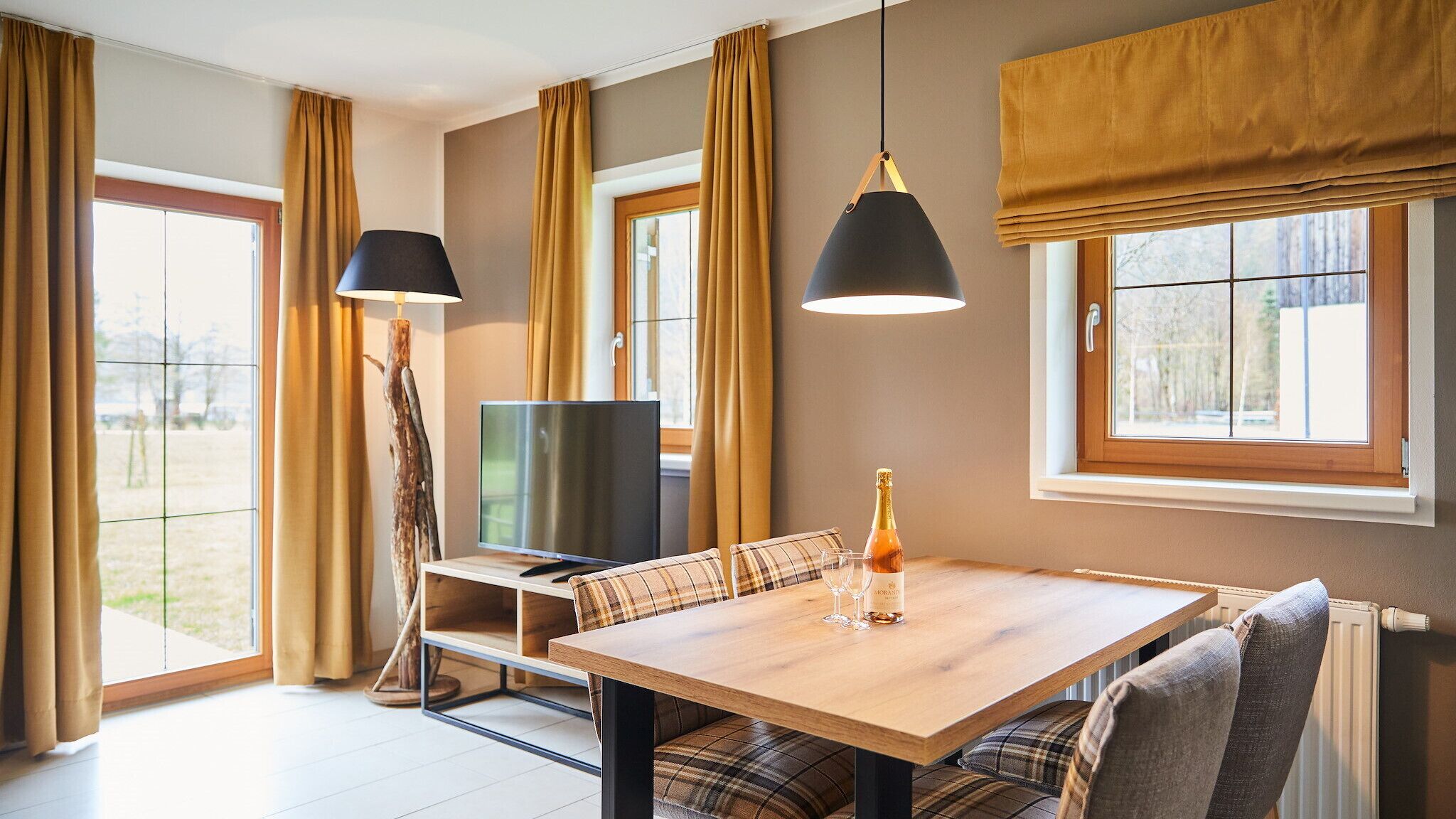 Una habitación acogedora con una mesa de madera, un sofá de cuadros y un televisor.
