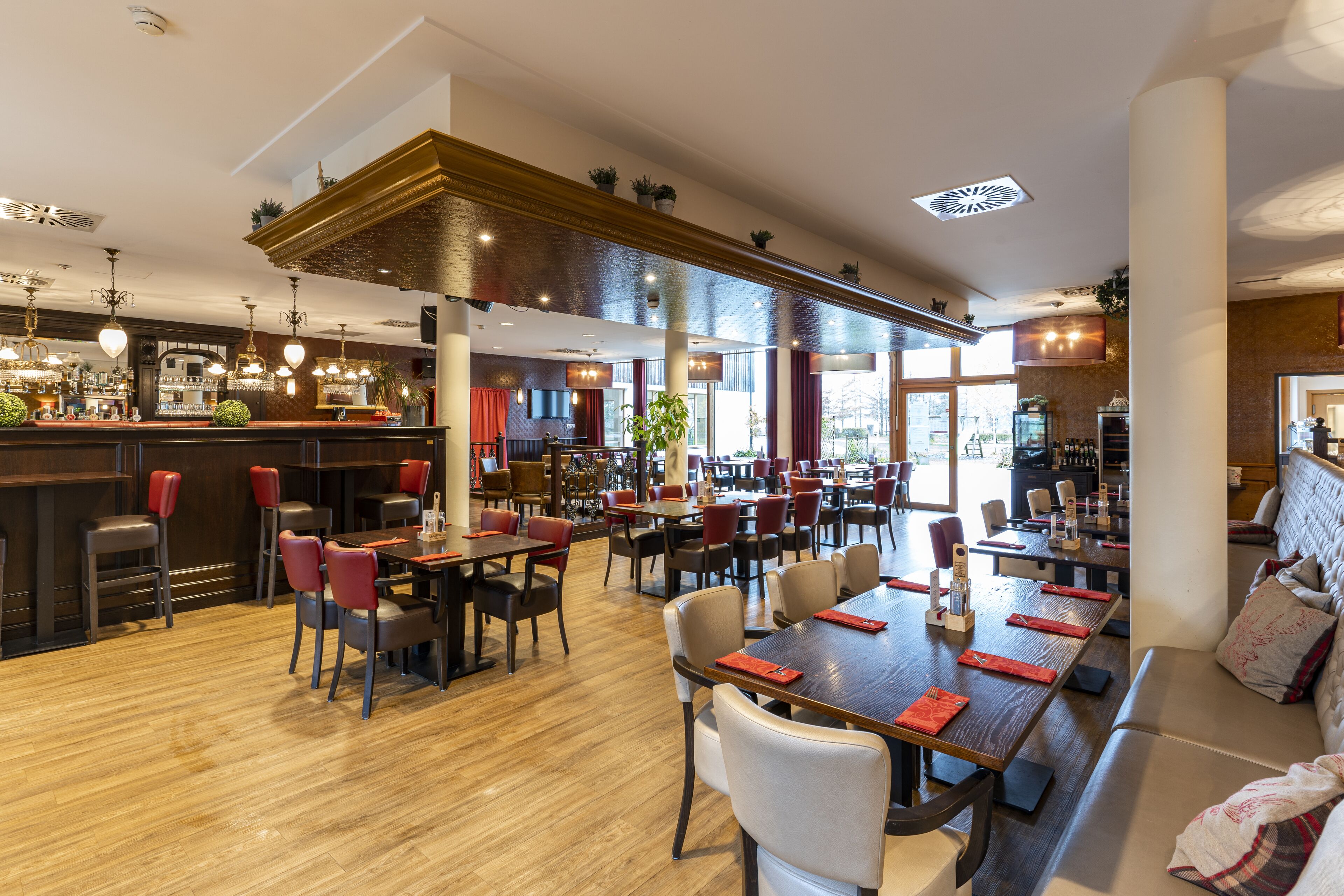A restaurant with multiple dining areas, a bar, and a seating area with a sofa.