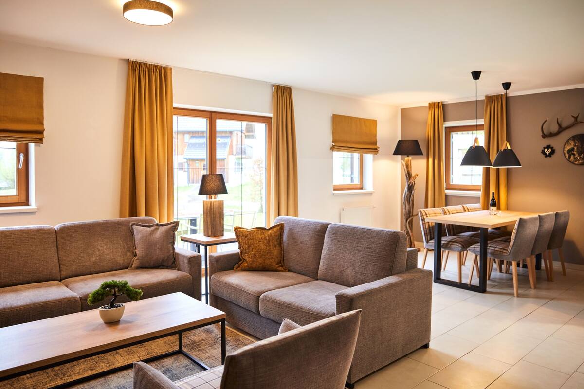 A modern living room with a sofa, coffee table, and dining area.