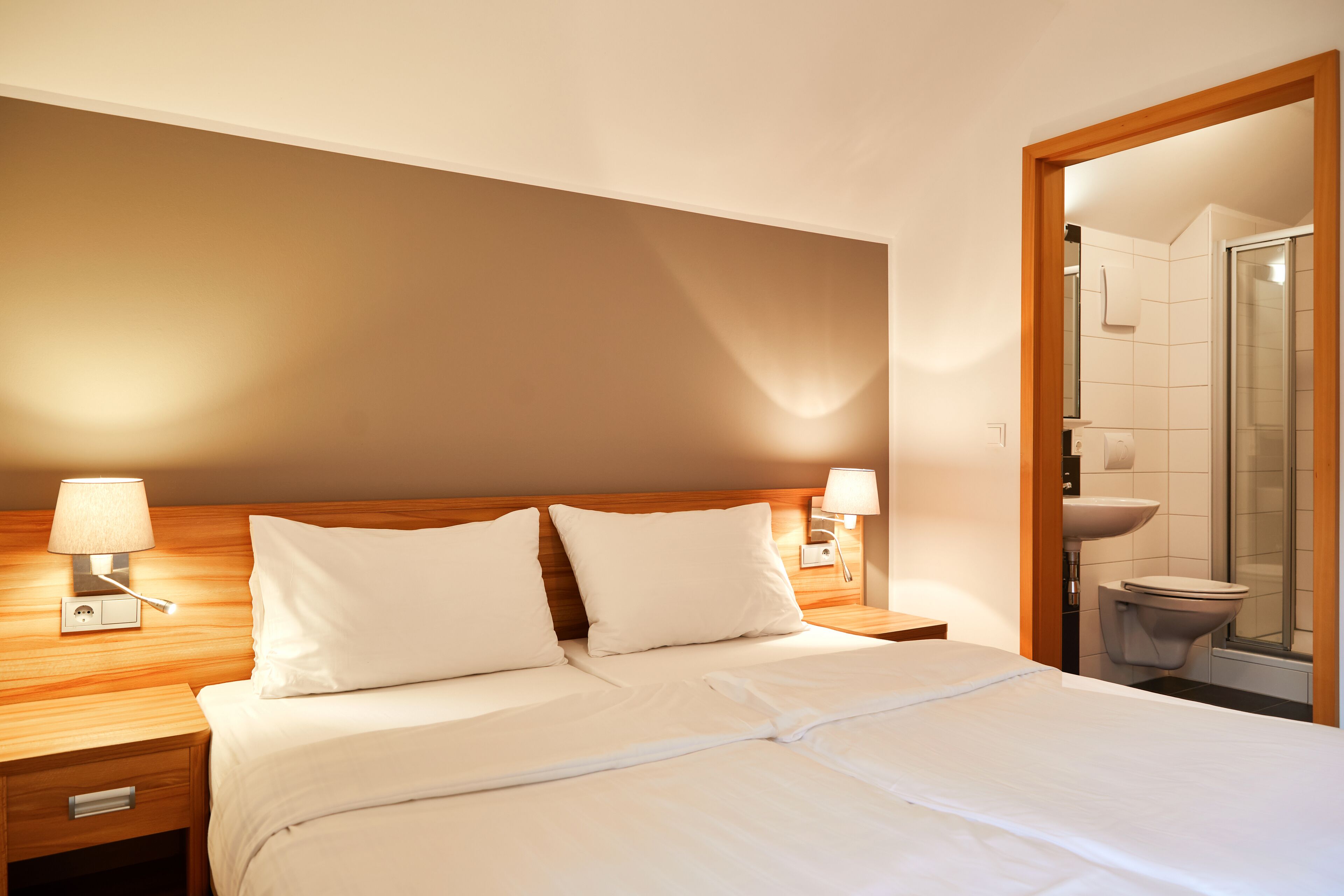 A hotel room with a bed, nightstands, and a bathroom visible through an open door.