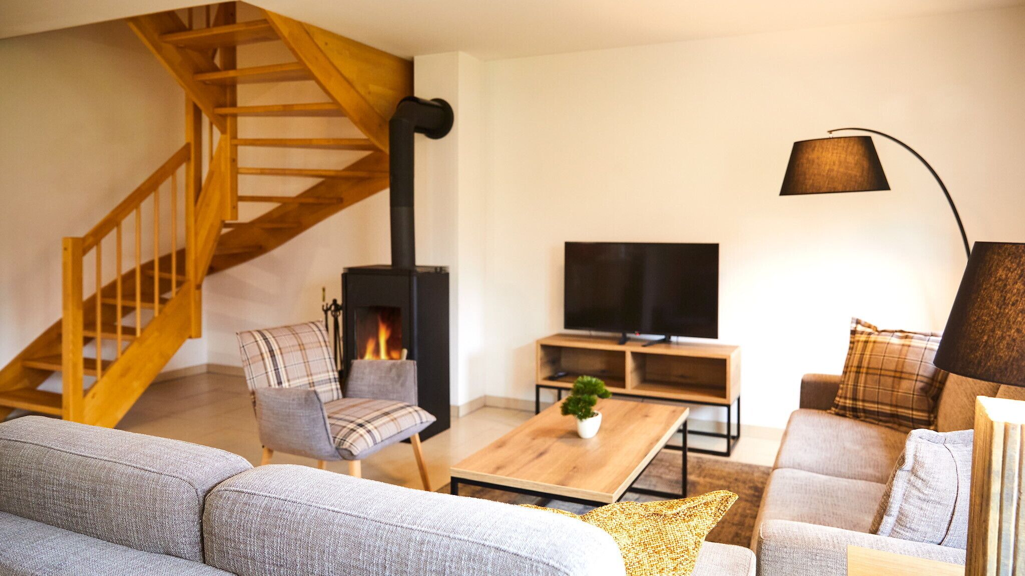 A living room with a wooden staircase, a fireplace, a television, and a sofa.