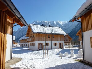 A wooden chalet with a snow-covered roof, surrounded by snow and mountains. - Dormio Resort Obertraun (Obertraun)