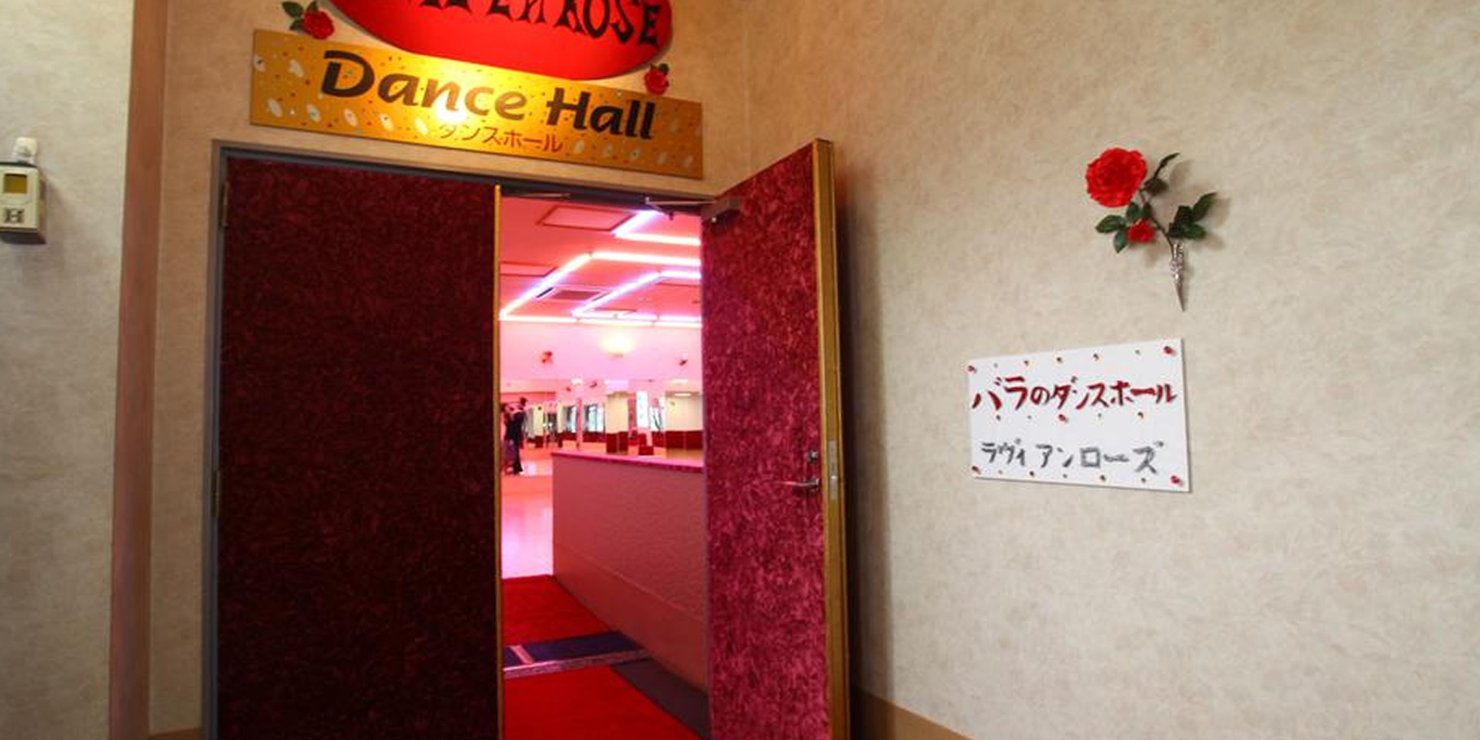 A hallway leading to a Dance Hall with a red carpet and a sign with Japanese text.