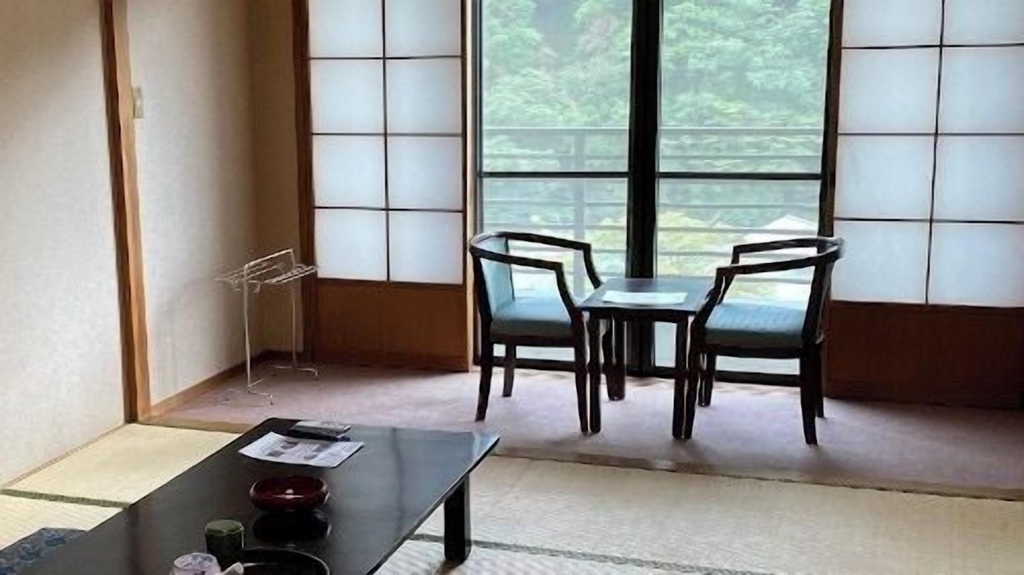 A traditional Japanese room with tatami flooring, a low table with a tea set, and a view through shoji screens.