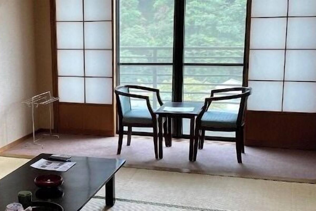 Ein traditioneller japanischer Raum mit Tatami-Bodenbelag, einem niedrigen Tisch mit Teeservice und Blick durch Shoji-Schirme.