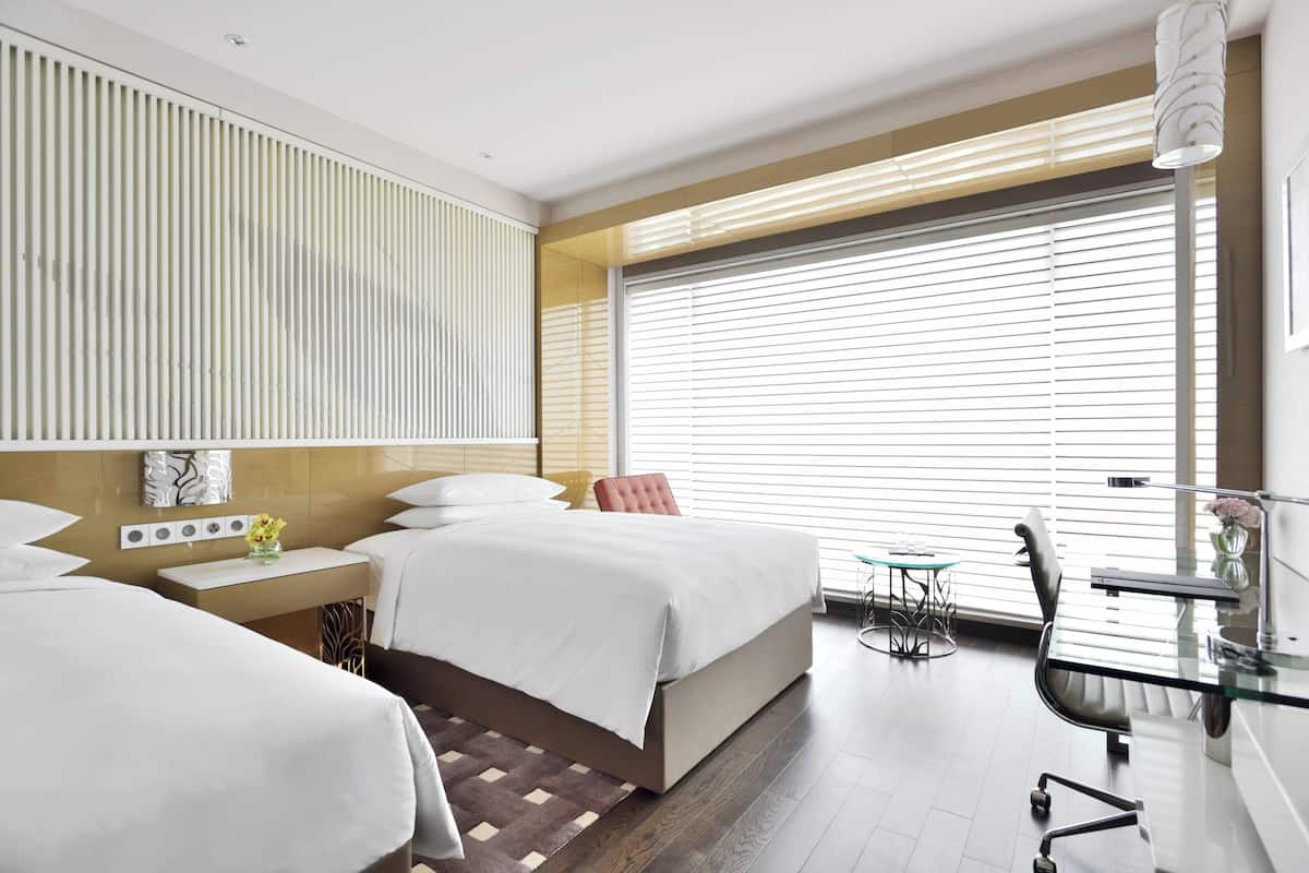 Una habitación de hotel moderna con una cama grande, mesitas de noche, un escritorio y una silla.