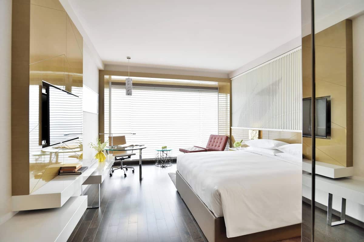 Una habitación de hotel moderna con una cama grande, un escritorio, una silla y un televisor.