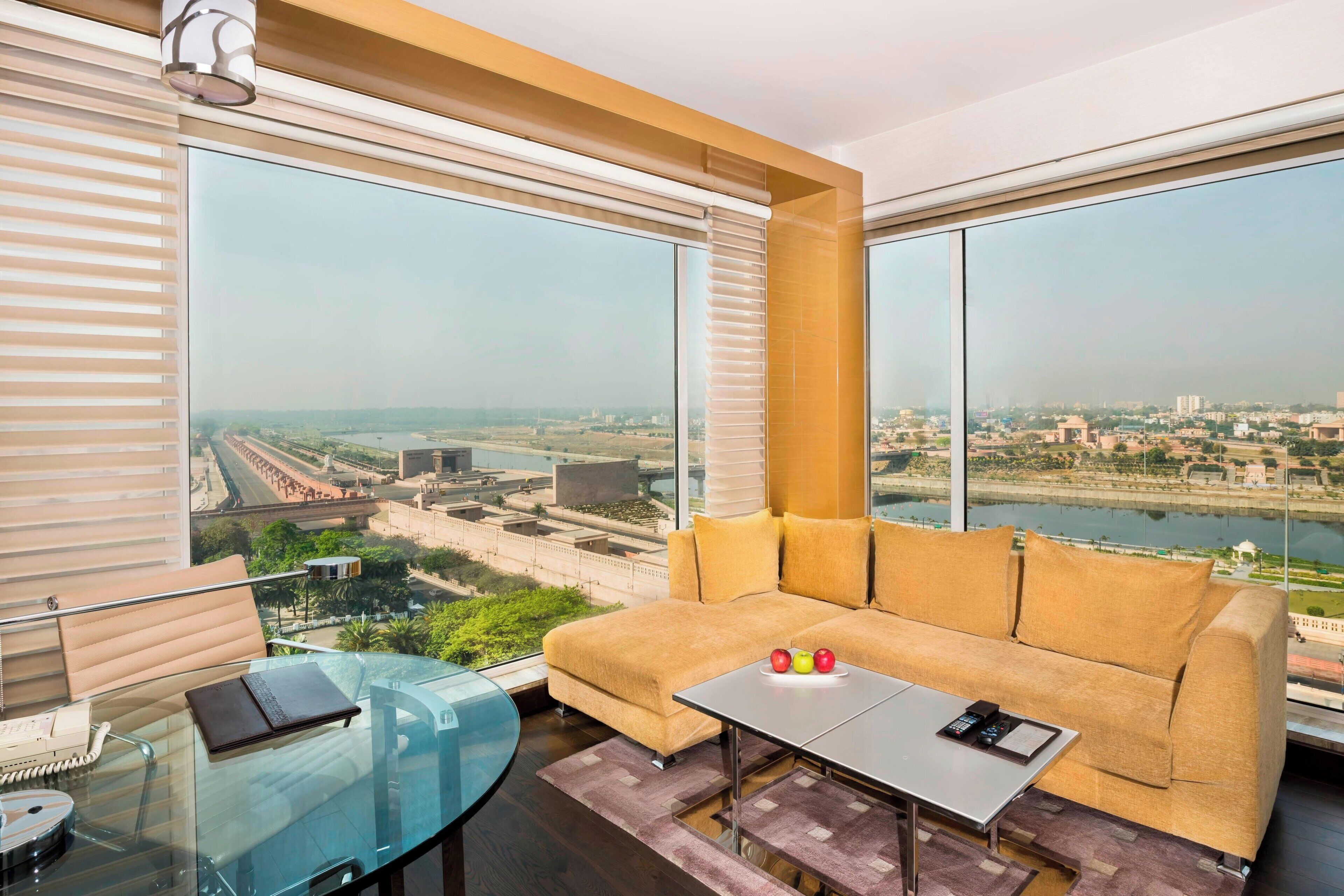 A modern room with a sofa, a glass table, and a view of a cityscape through large windows.