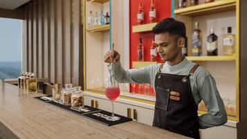 A bar area with a bartender, shelves with bottles, and a bar counter with glasses and bottles.