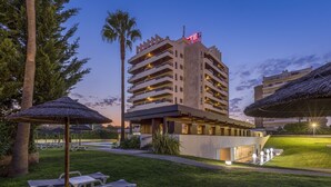 Un hotel con piscina, sillas de descanso y un césped bien cuidado.