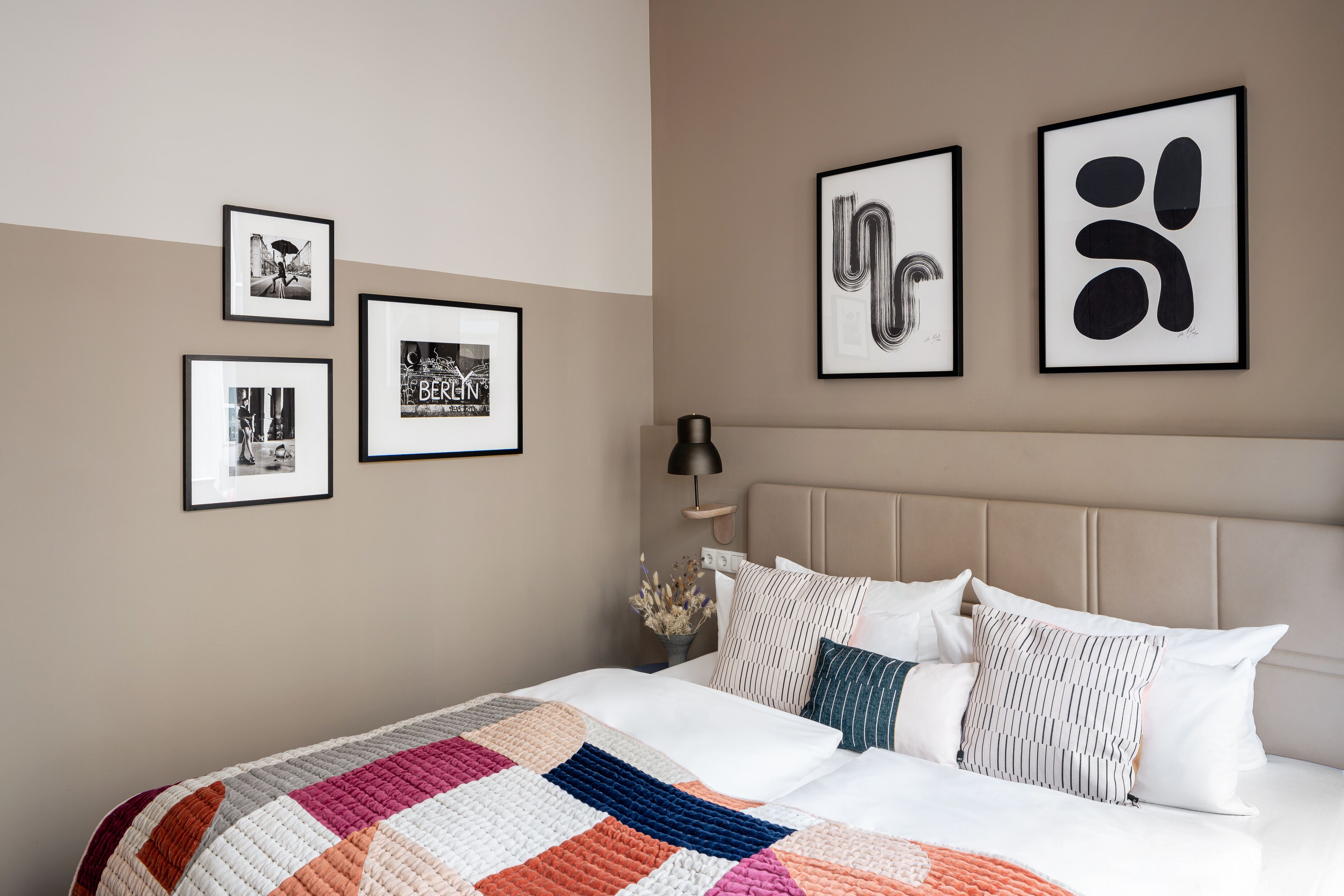 A neatly arranged bedroom with a bed, pillows, and framed pictures on the wall.