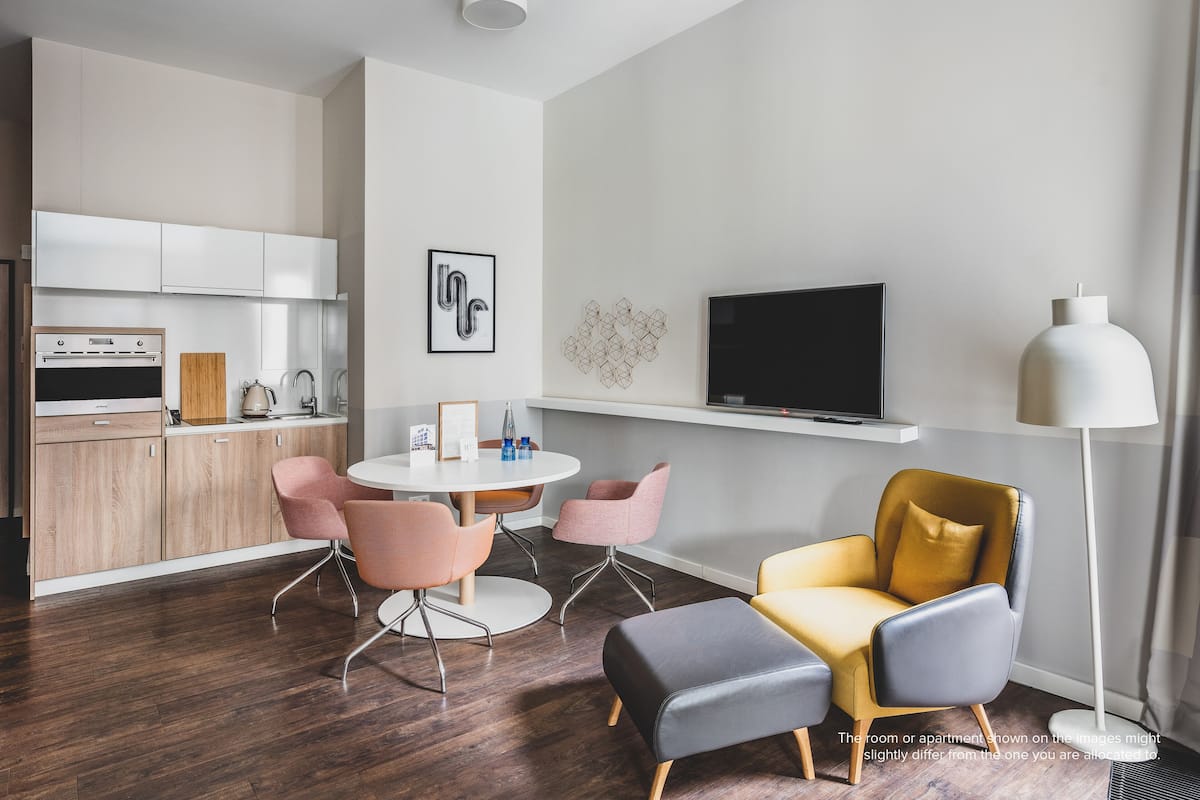 Uma sala de estar moderna com área de jantar, cozinha e televisão.