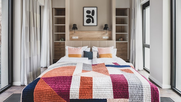 Una camera da letto moderna con un letto grande, scaffalature integrate e vista dalla finestra.