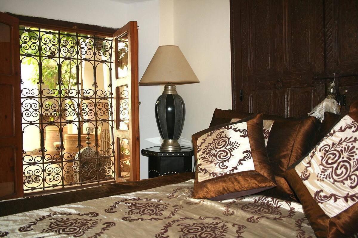 A bedroom with a bed, a lamp, and a wooden door.