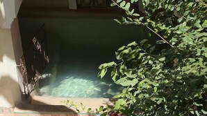 Une cour avec une piscine, un canapé rouge et une petite table agrémentée d’un arrangement floral.
