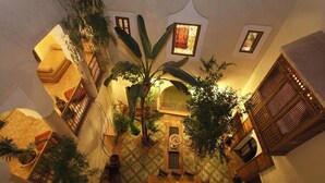 Une cour avec une table en bois, des plantes en pot et un sol carrelé.